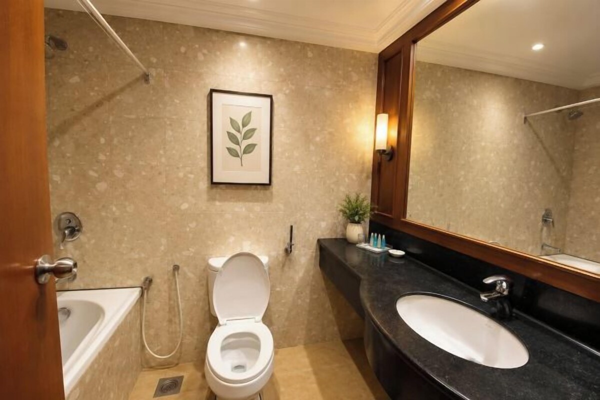 Ein Badezimmer mit Badewanne, Toilette, Waschbecken und einem großen Spiegel.