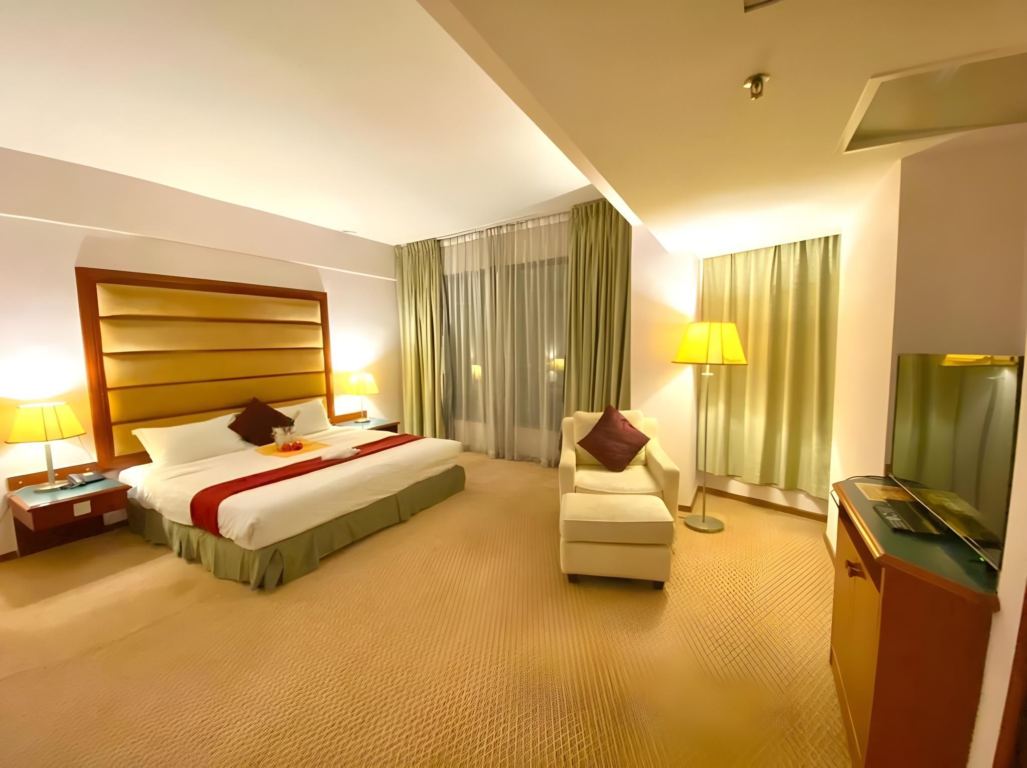 A hotel room with a large bed, a chair, a desk, and a television.