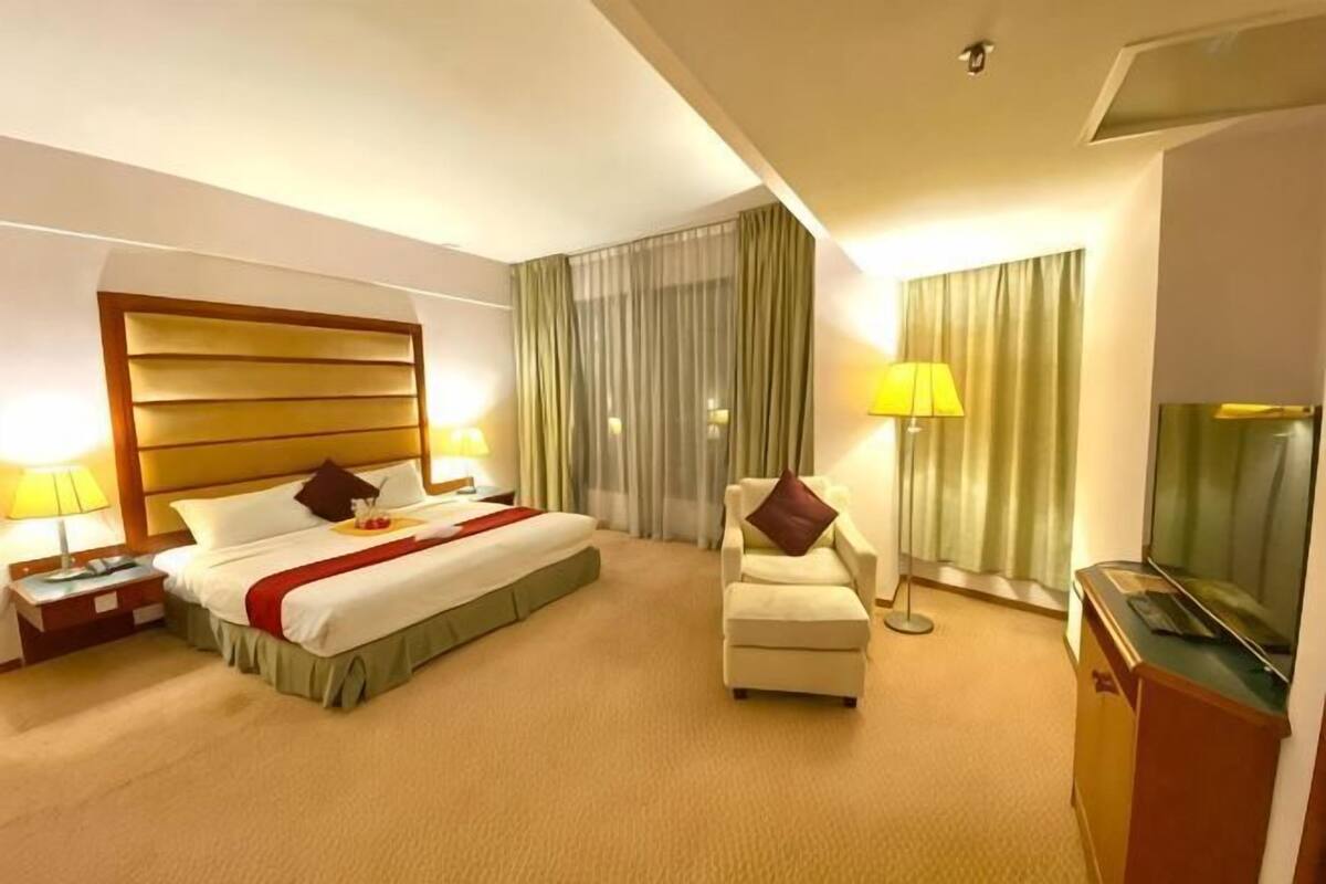 Habitació d'hotel amb un llit, una cadira, escriptori, televisió i cortines.