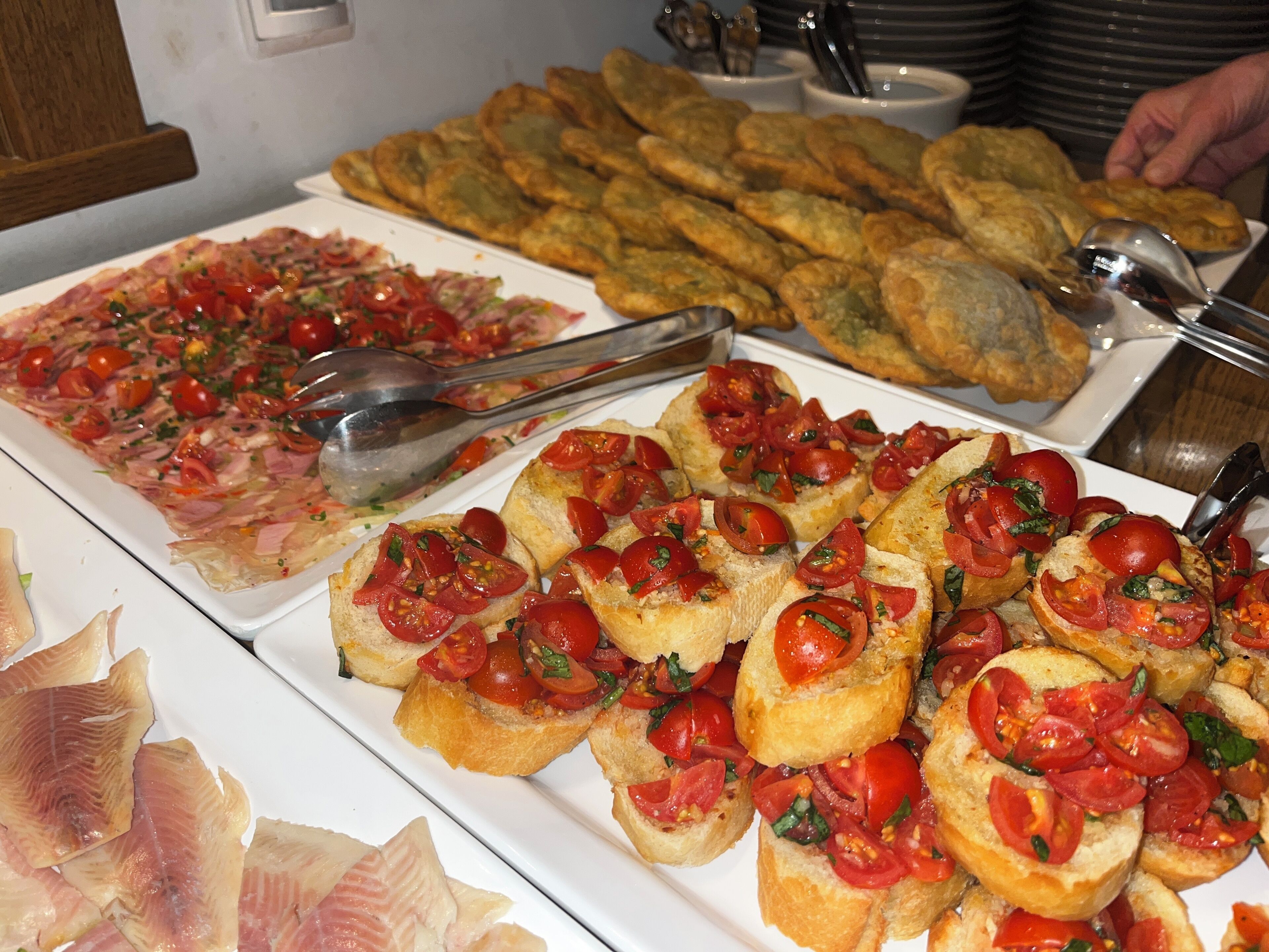 Un bufé con diversas opciones de comida, incluyendo pan, pescado y pizza.