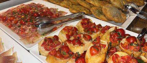 Un bufé con diversas opciones de comida, incluyendo pan, pescado y pizza.