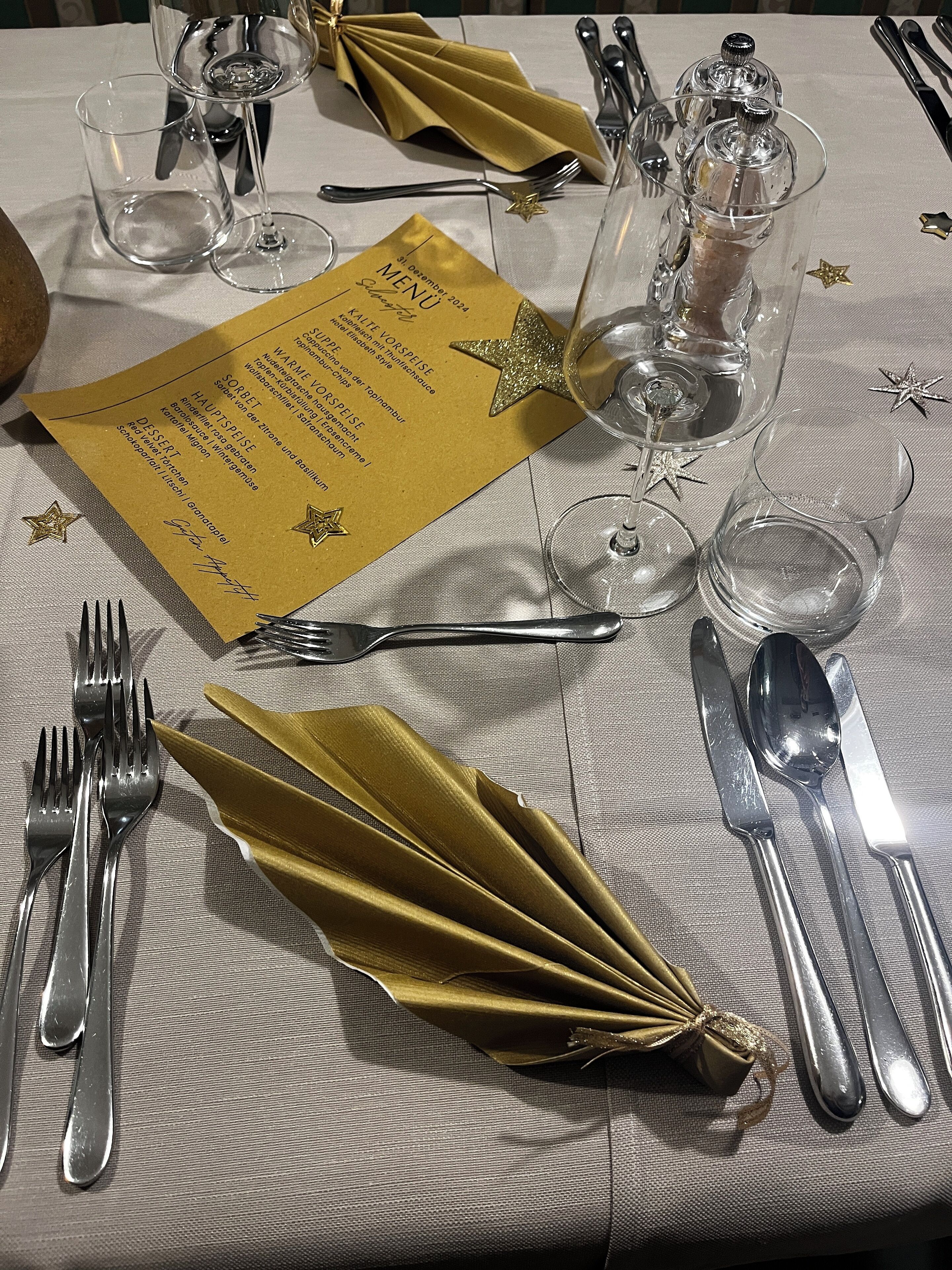 Ein gedeckter Tisch mit Speisekarte, Besteck und Gläsern, der ein Essensangebot andeutet.
