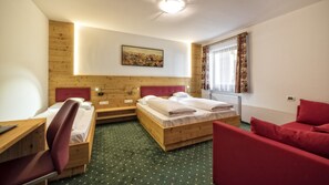 Et hotelværelse med to senge i træ, et skrivebord, en stol og en rød sofa.