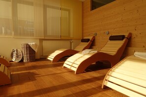 A room with three wooden massage beds, a wicker basket, and a radiator. - Hotel Elisabeth (Chienes)