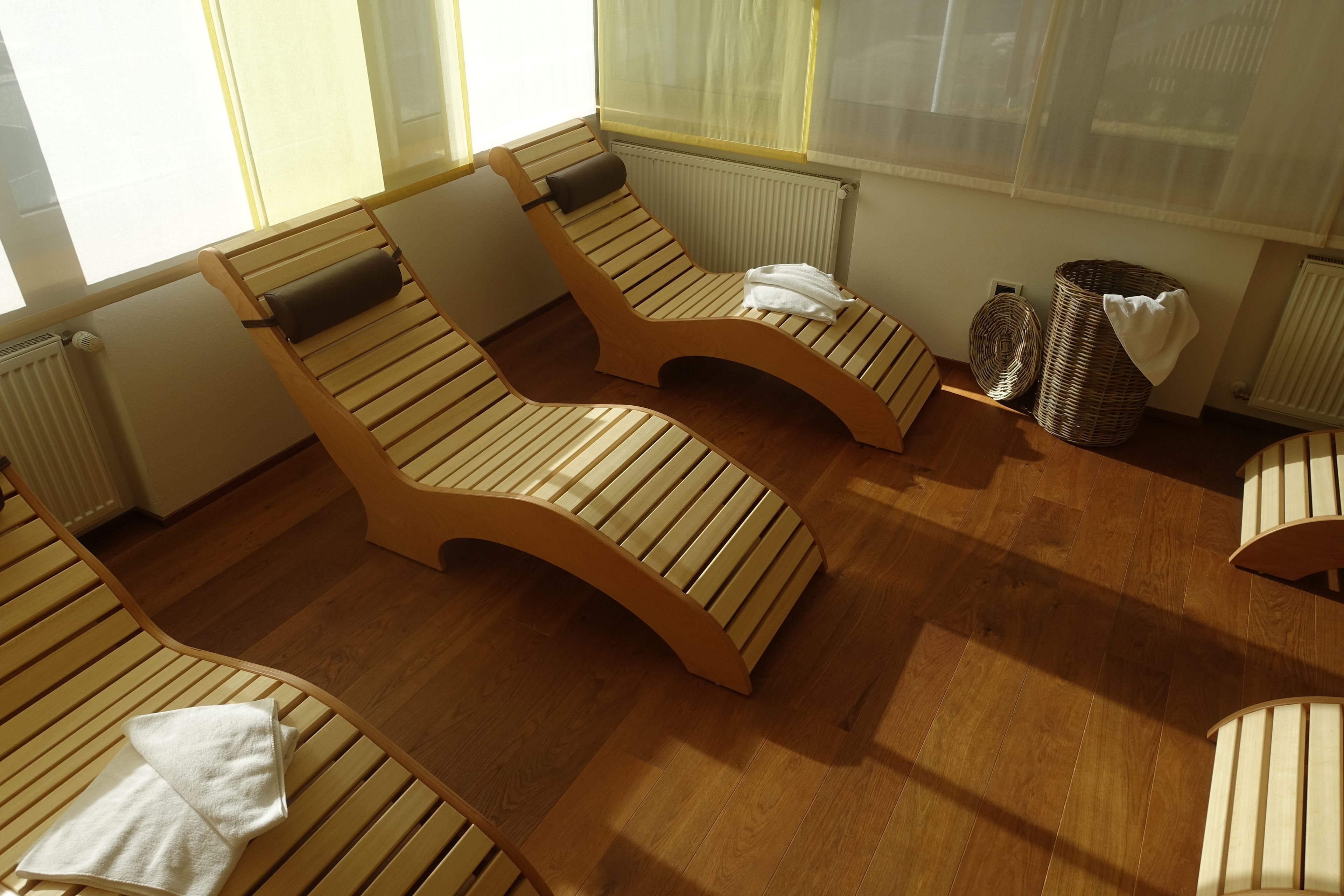 Une pièce avec des tables de massage en bois, un radiateur et un panier en osier.