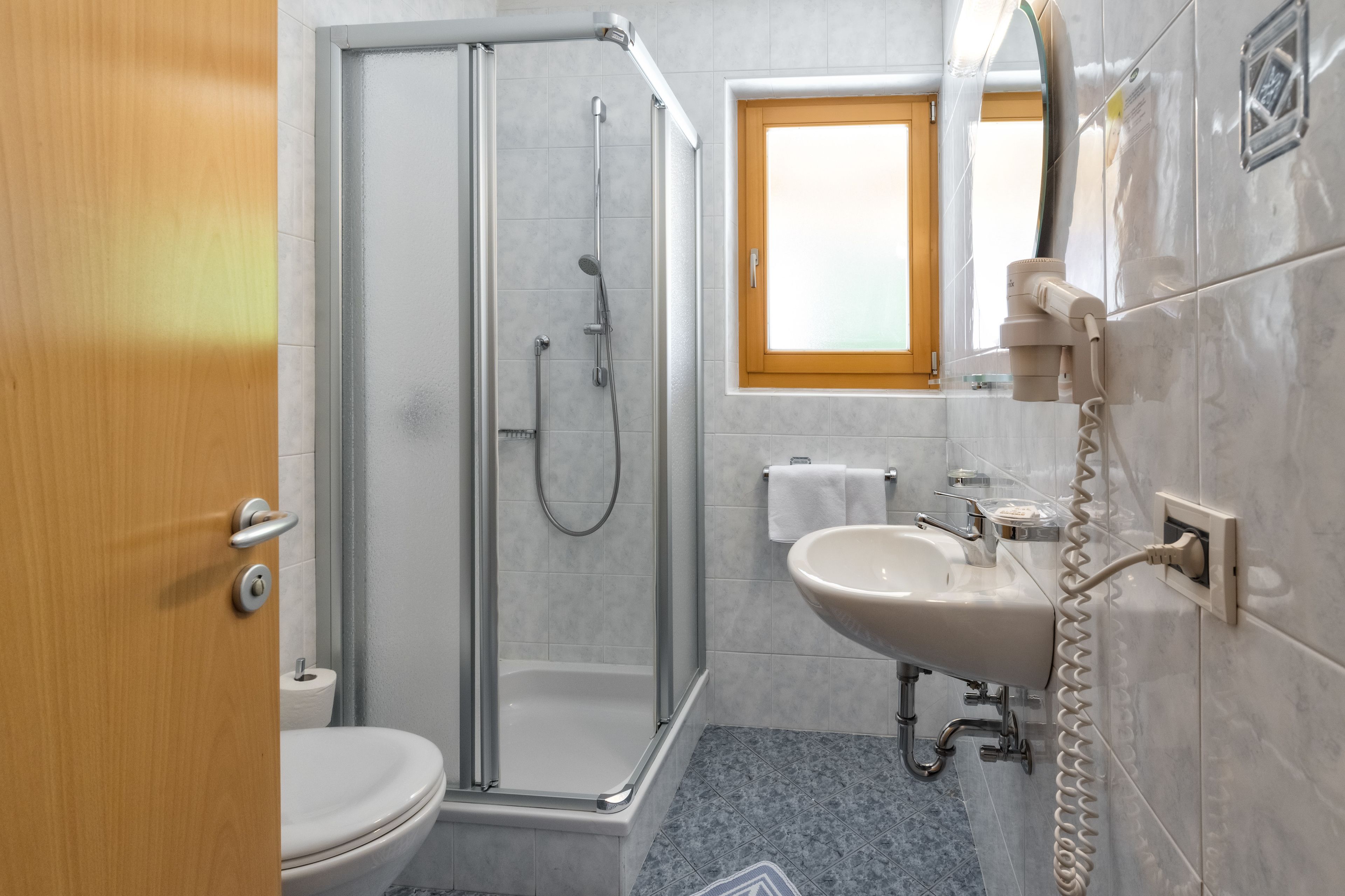 A bathroom with a glass-enclosed shower, a sink, and a toilet.