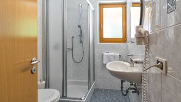 A bathroom with a glass-enclosed shower, a sink, and a toilet.