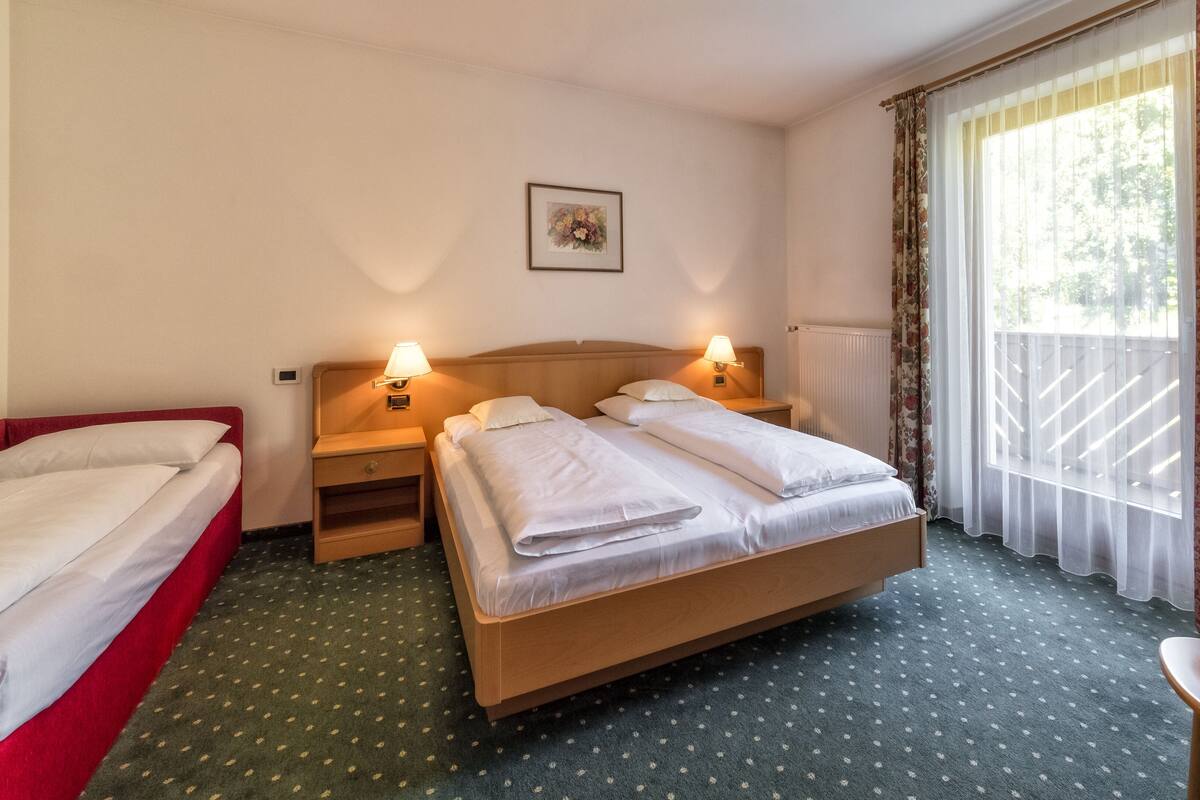 Habitación de hotel con cama doble, cama individual, escritorio y silla.