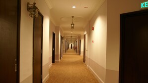 Un pasillo de hotel con varias puertas, suelo alfombrado y una lámpara en el techo.