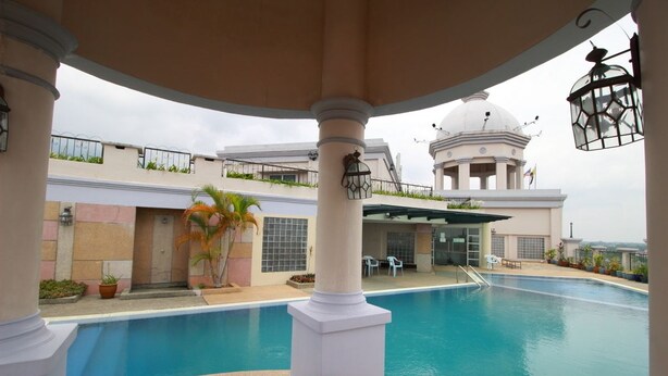 Zona de piscina con un pabellón, palmeras y un edificio con cúpula al fondo.