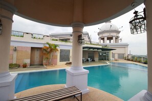 A swimming pool area with a pavilion, palm trees, and a building with a dome in the background. - Grand Kampar Hotel (Kampar)