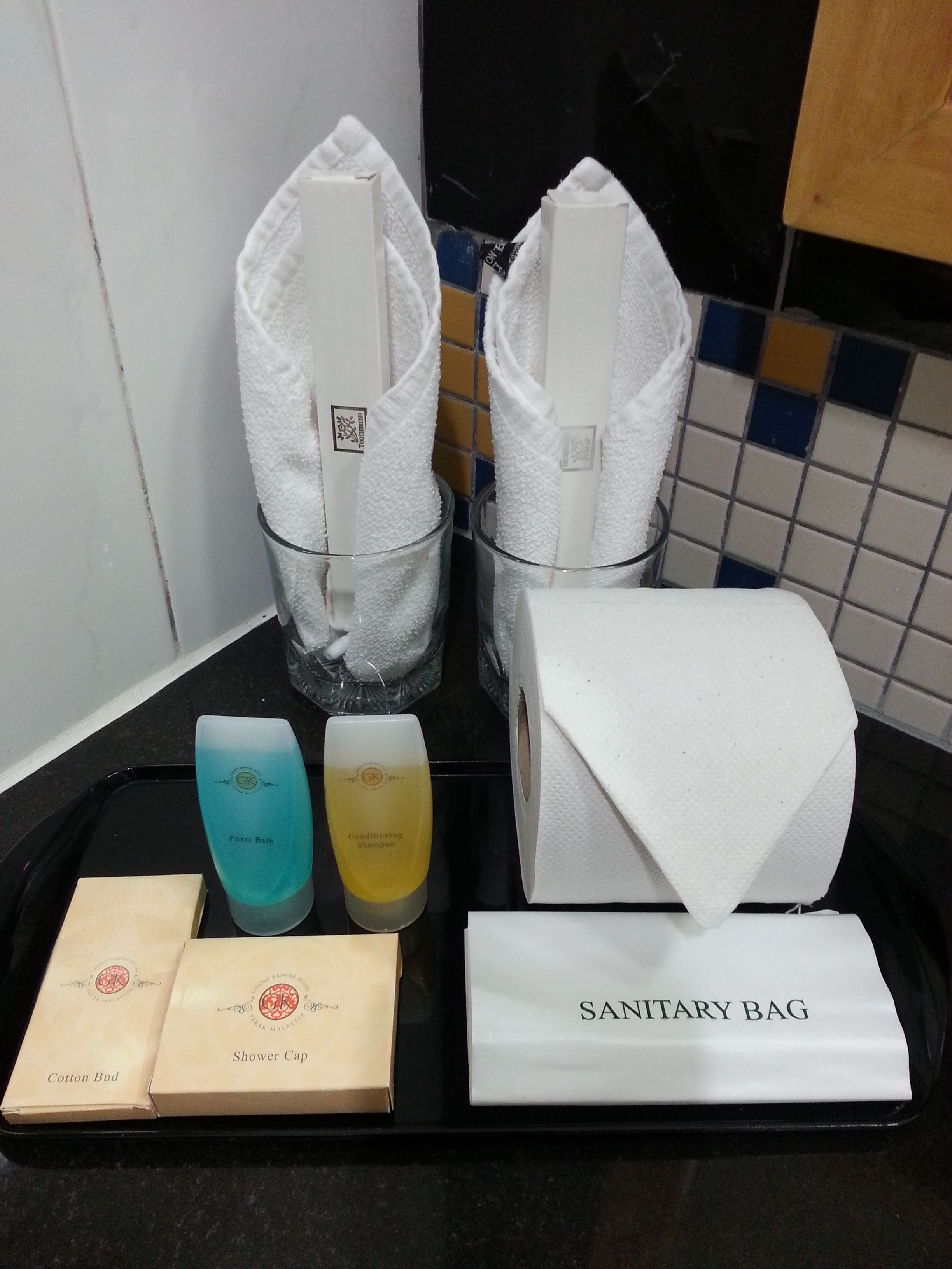 A tray with toiletries including a shower cap, cotton bud, foam bath, and conditioning shampoo.