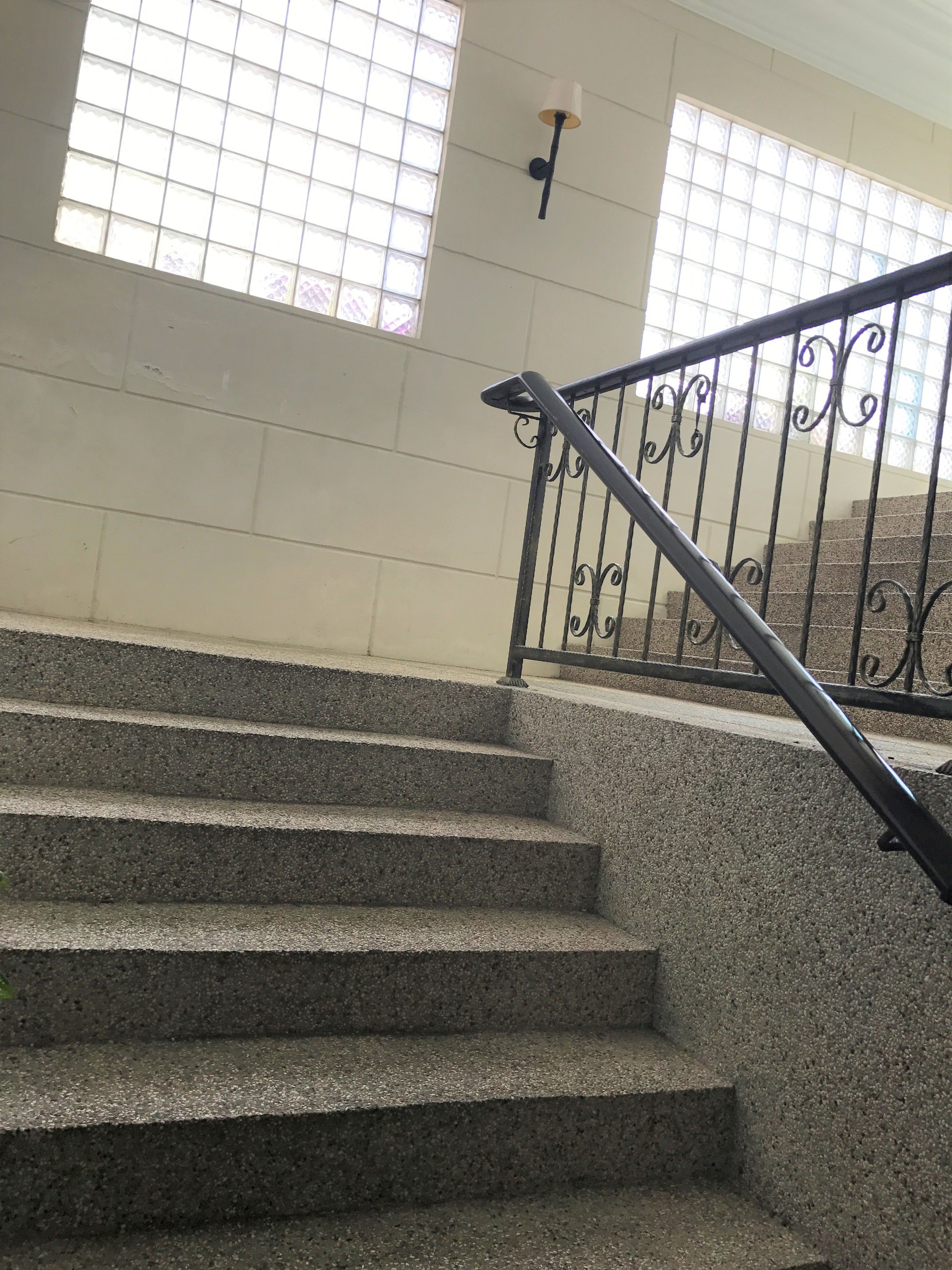 A staircase with a metal railing and a wall-mounted light fixture.
