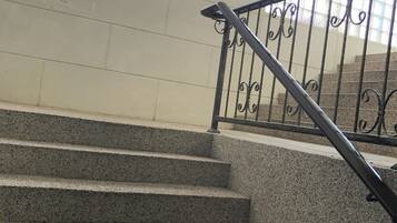 A staircase with a metal railing and a wall-mounted light fixture.