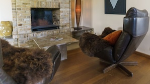A living room with a stone fireplace, a leather recliner, and a coffee table. - Hotel St-Janshof (Waregem)
