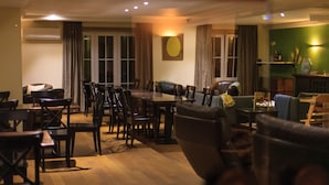A dining area with a long table and multiple chairs, a sofa, and a small table with a lamp. - Hotel St-Janshof (Waregem)