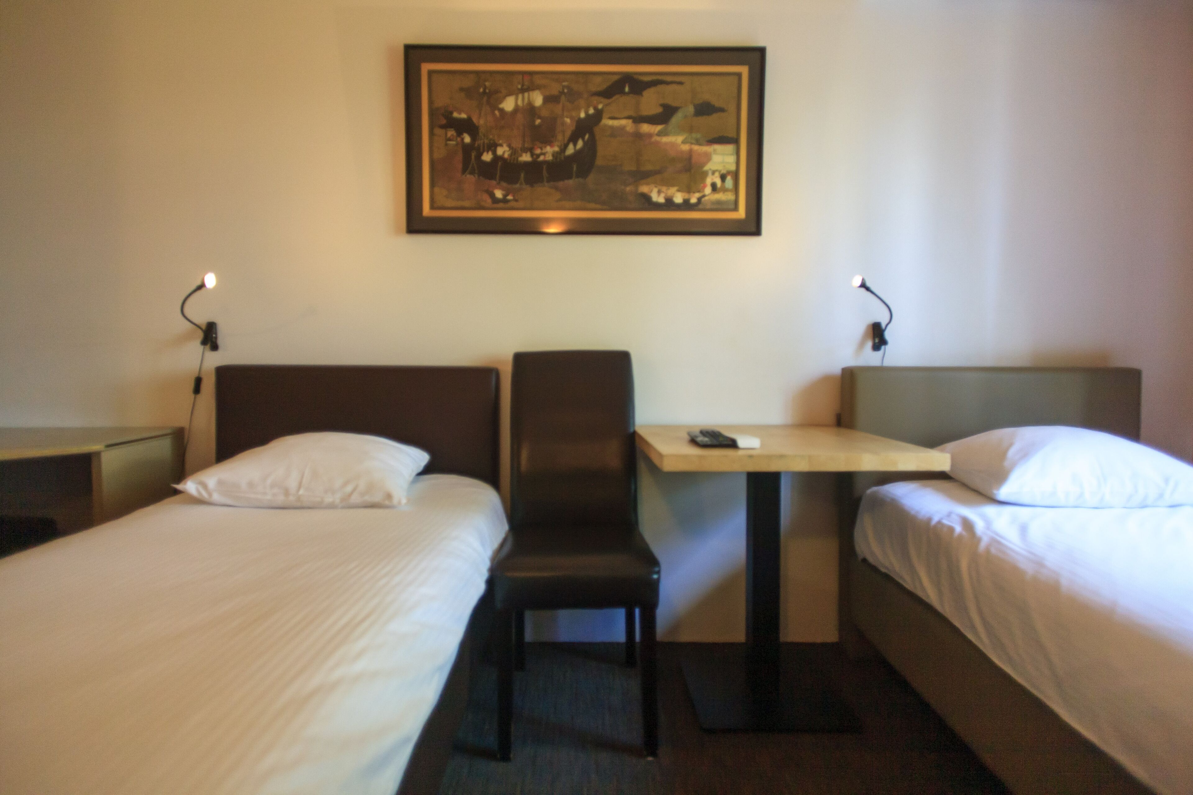 Habitación de hotel con dos camas, un escritorio y una silla.