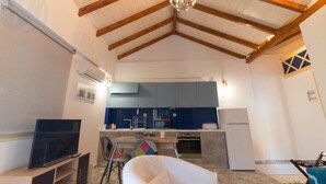 Un espacio habitable compacto con cocina, una mesa de comedor y un televisor.