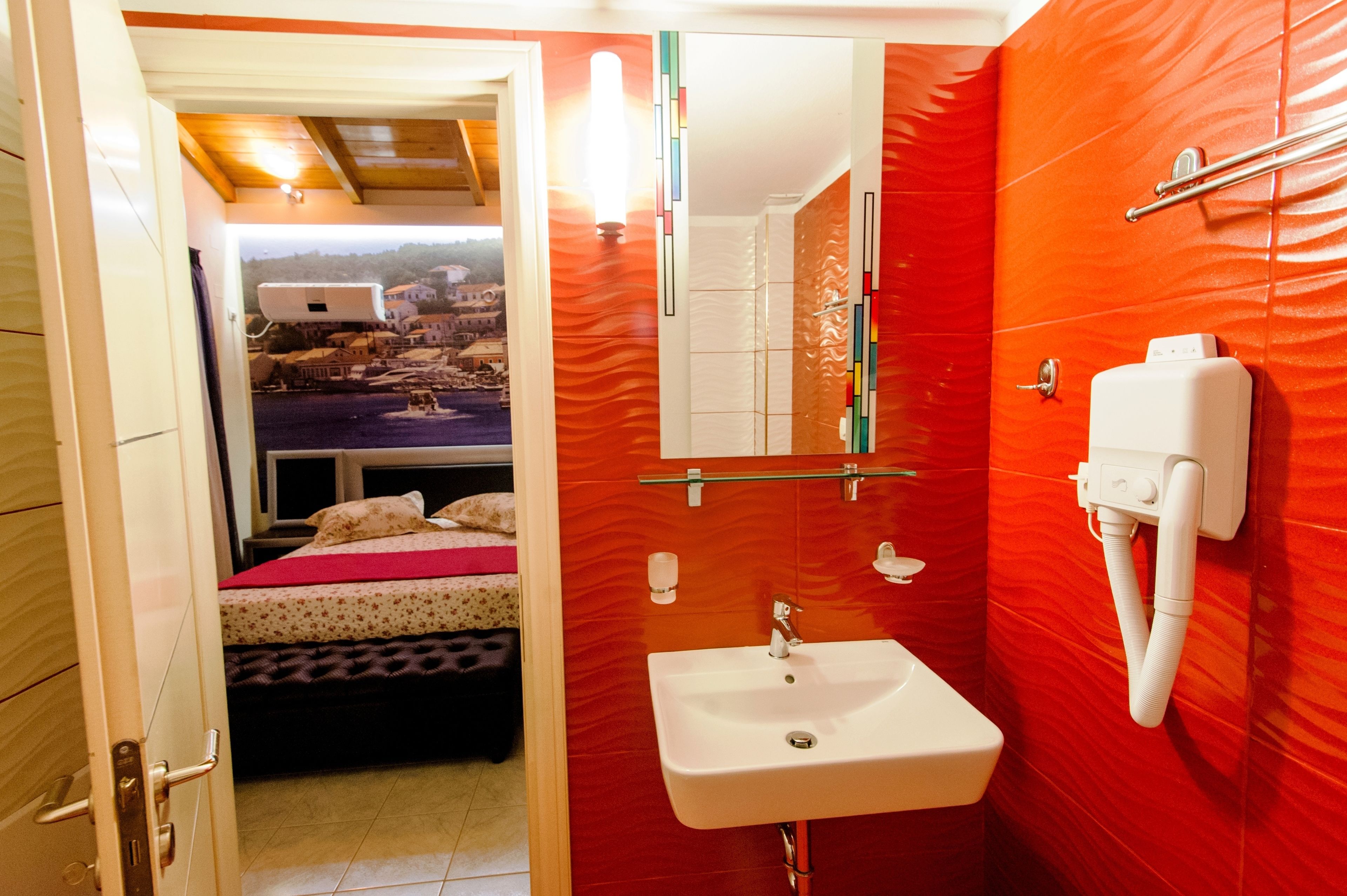 Une salle de bain avec un mur rouge, un lavabo blanc et un miroir.