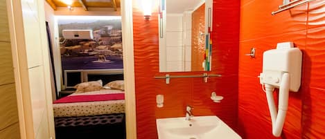 A bathroom with a red wall, a white sink, and a mirror.