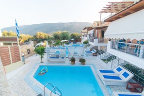 A swimming pool with lounge chairs, a diving board, and a view of mountains. - All Saints Villas (Igoumenitsa)