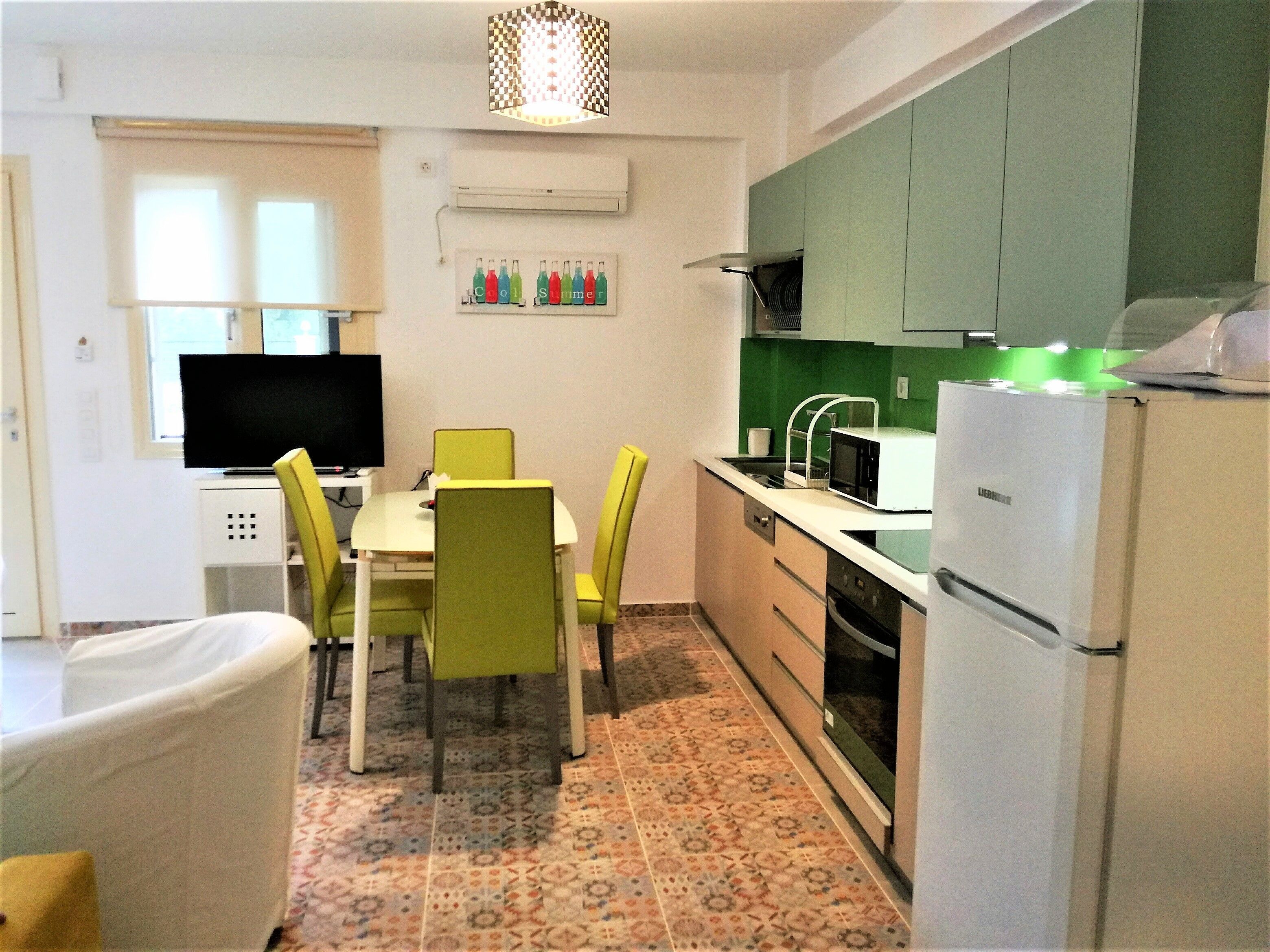 Cocina compacta con comedor, televisor de pantalla plana y refrigerador.