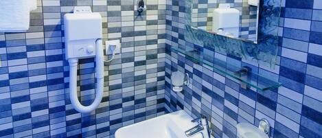 Un baño con salpicadero de azulejos, un lavamanos, un espejo y un perchero para toallas.