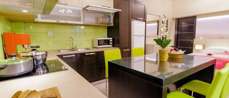 A modern kitchen with a central island, bright green chairs, and a refrigerator.