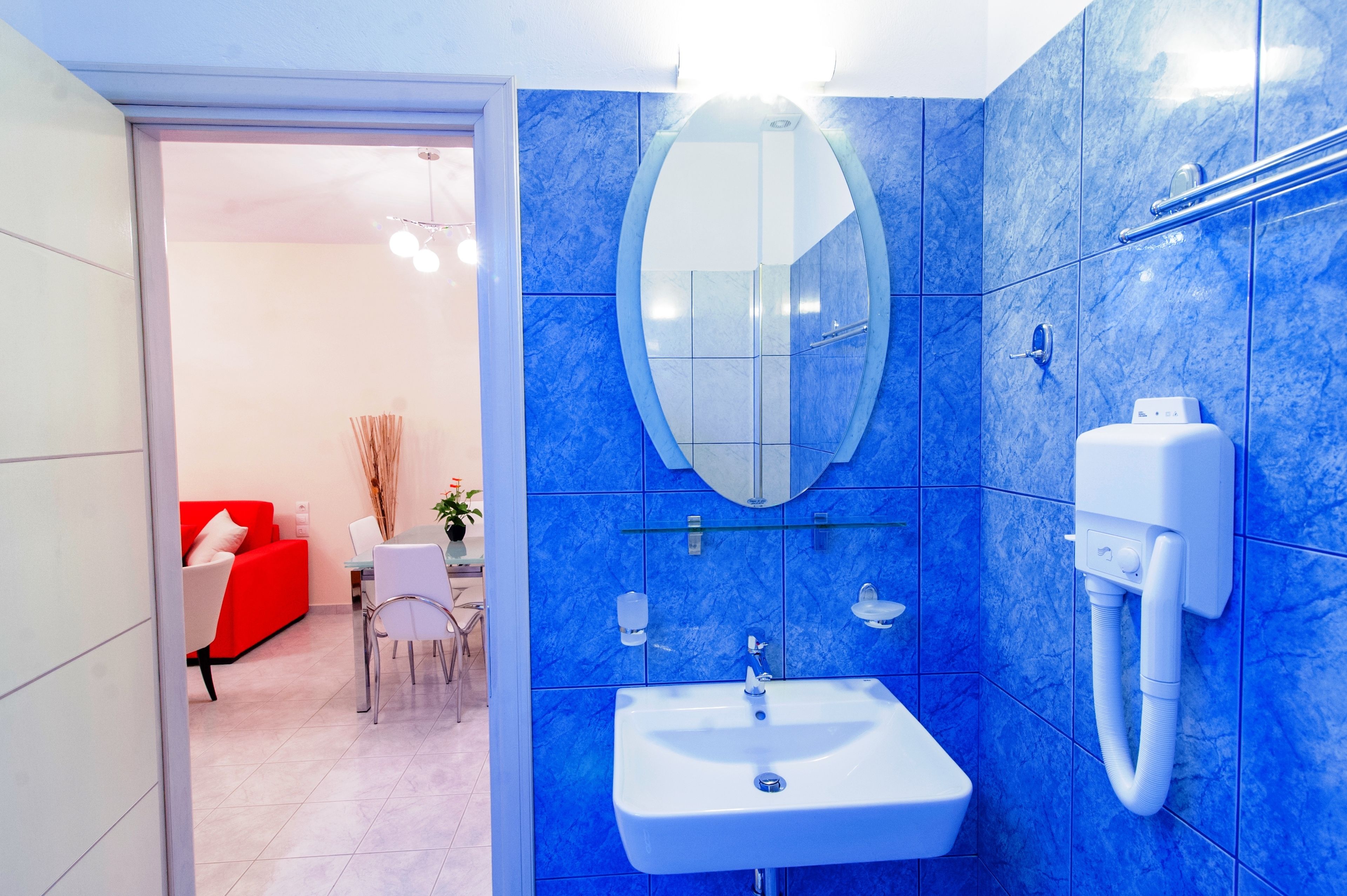 A bathroom with a blue marble wall, a white sink, a mirror, and a shower area.