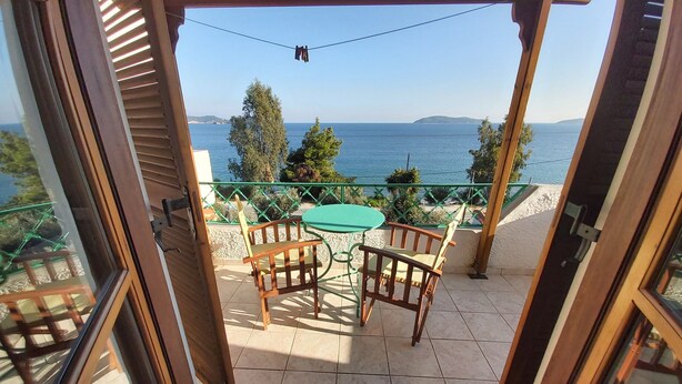 An open balcony with a table and chairs, a view of the sea, and a green railing. - Azalea Studios (Skiathos)