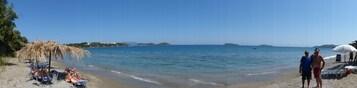 Una playa con aguas cristalinas, sombrillas y sillas de descanso.