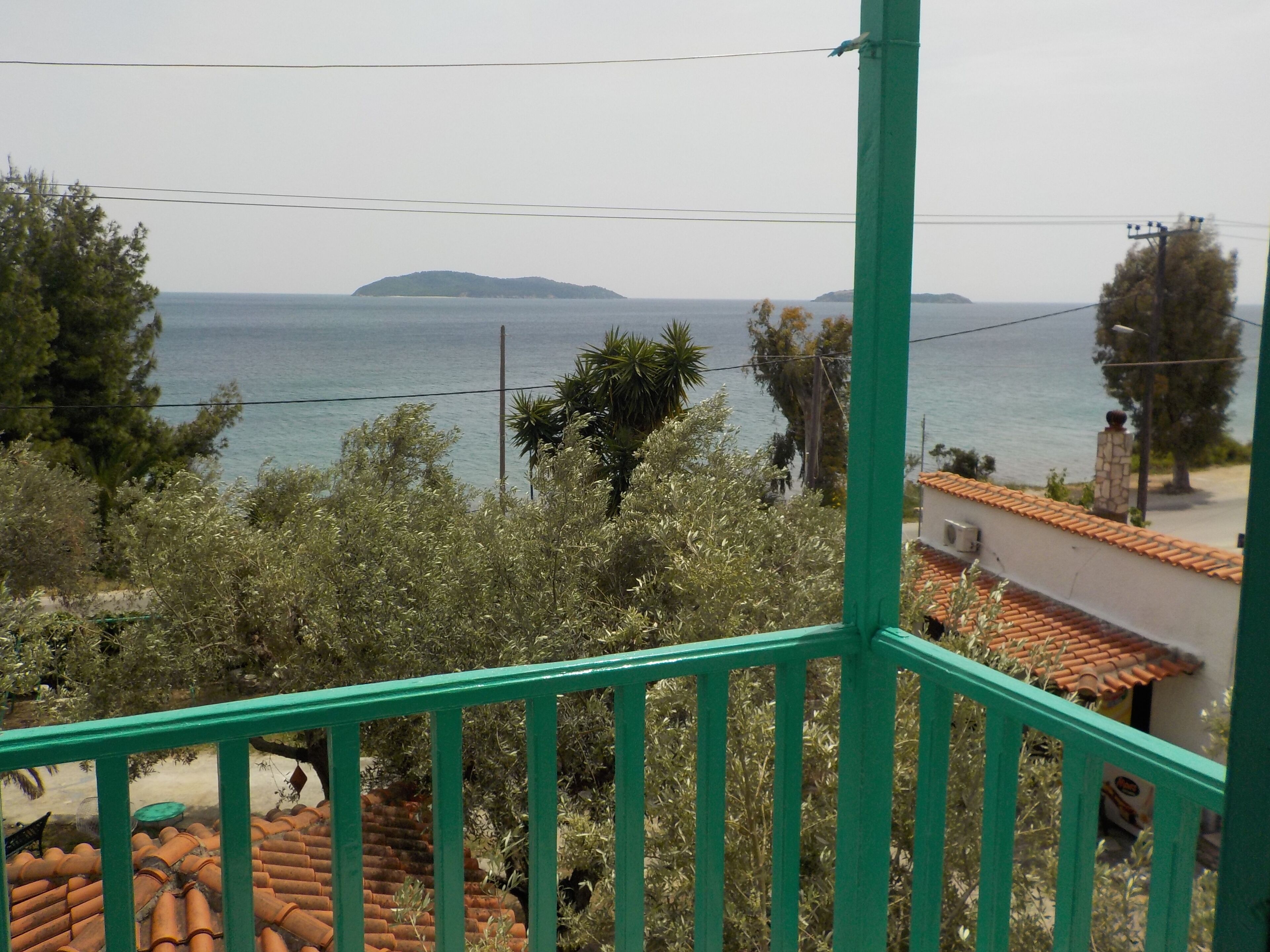 A balcony with a view of the sea and distant hills.