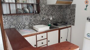 A kitchen with a wooden countertop, a sink, and a patterned backsplash. - Azalea Studios (Skiathos)