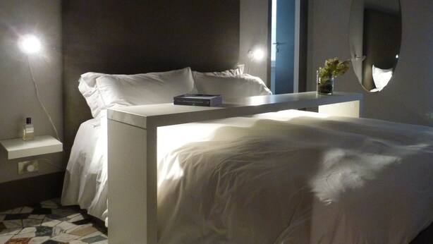 Un dormitorio moderno con cama, mesita de noche y un espejo grande.