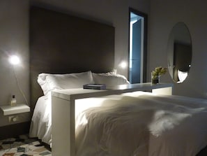 Ein modernes Schlafzimmer mit Bett, Nachttisch und einem großen Spiegel.