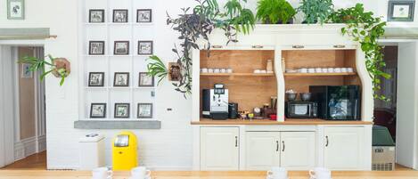 A kitchen with white cabinets, a coffee machine, and various plants.