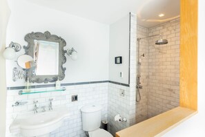 A bathroom with a white sink, mirror, and toilet, a shower with a glass enclosure, and a wooden vanity.