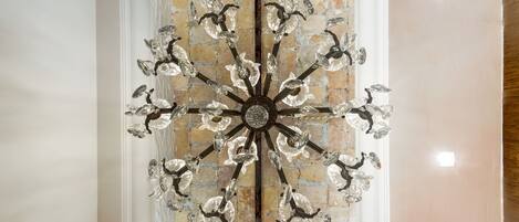 A chandelier with multiple arms and crystal decorations against a brick wall.