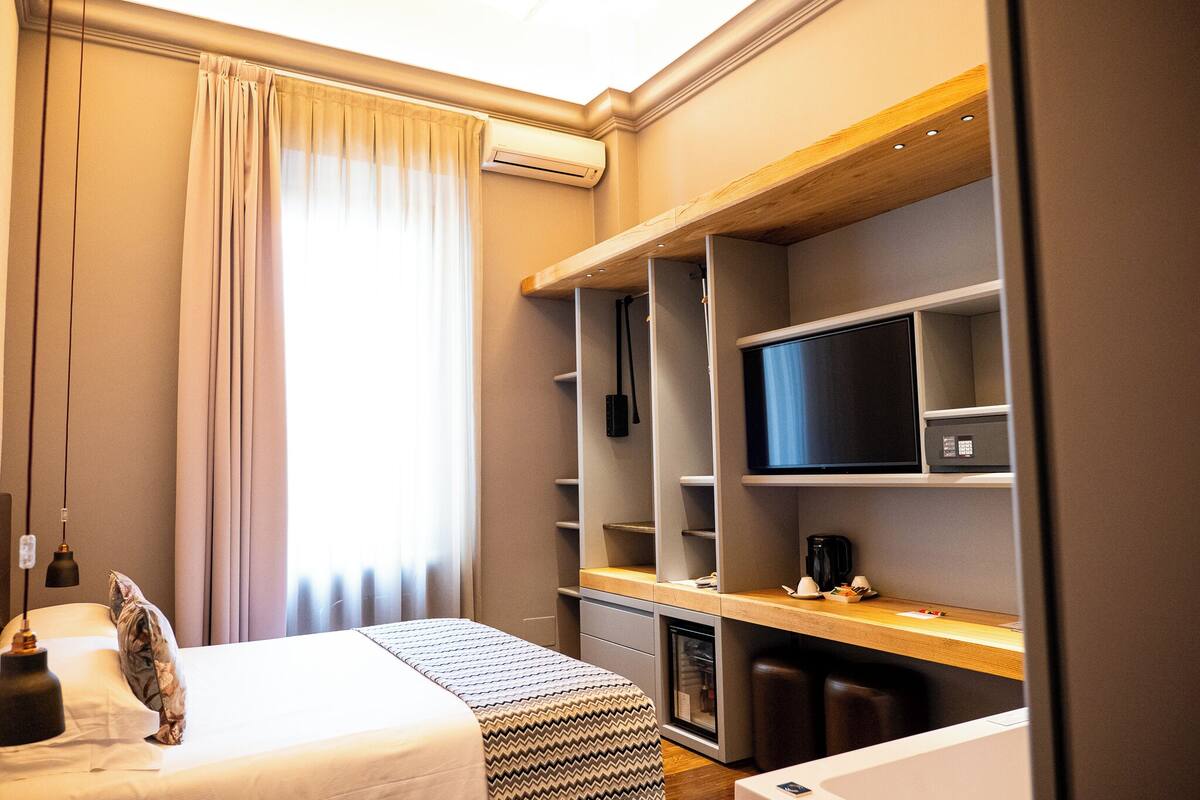 A hotel room with a bed, a TV, a desk, and a wardrobe.