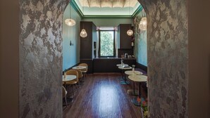 An interior with a rustic stone archway, wooden flooring, and round tables with chairs. - New Design St. Peter (Rome)