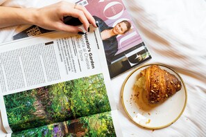 A magazine on a bed with a partially eaten croissant and a plate with crumbs. - New Design St. Peter (Rome)