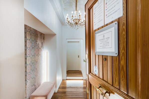 A hallway with a wooden door, a bench, and a chandelier. - New Design St. Peter (Rome)