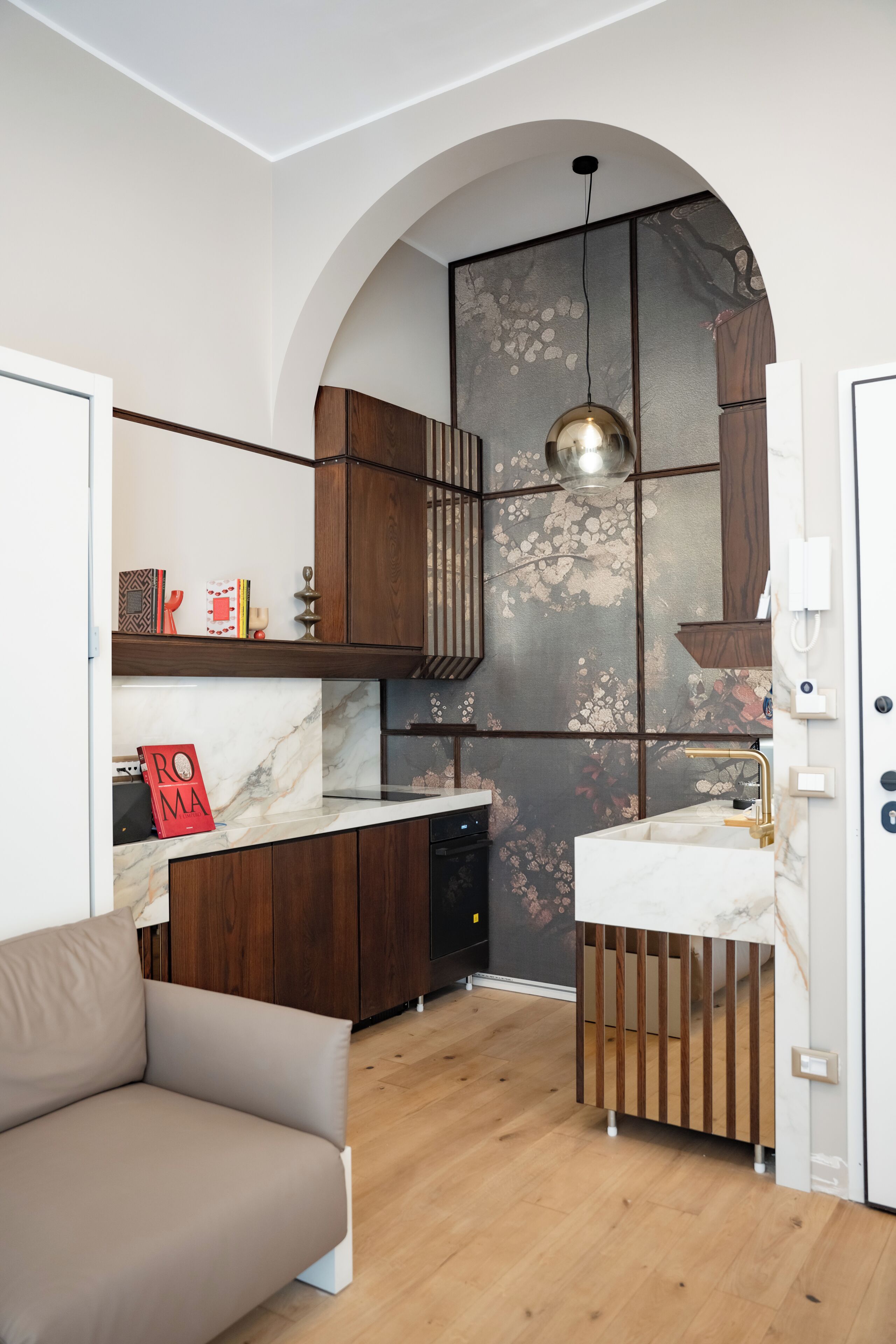 A modern kitchen with a marble countertop, wooden cabinets, and a built-in oven.