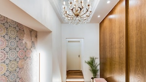 A hallway with a patterned wall, a wooden bench, a potted plant, and a door at the end. - New Design St. Peter (Rome)