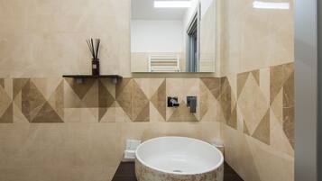 Un bagno moderno con un lavabo a forma di coppa ampio, uno specchio sopra e un parete con motivo geometrico.
