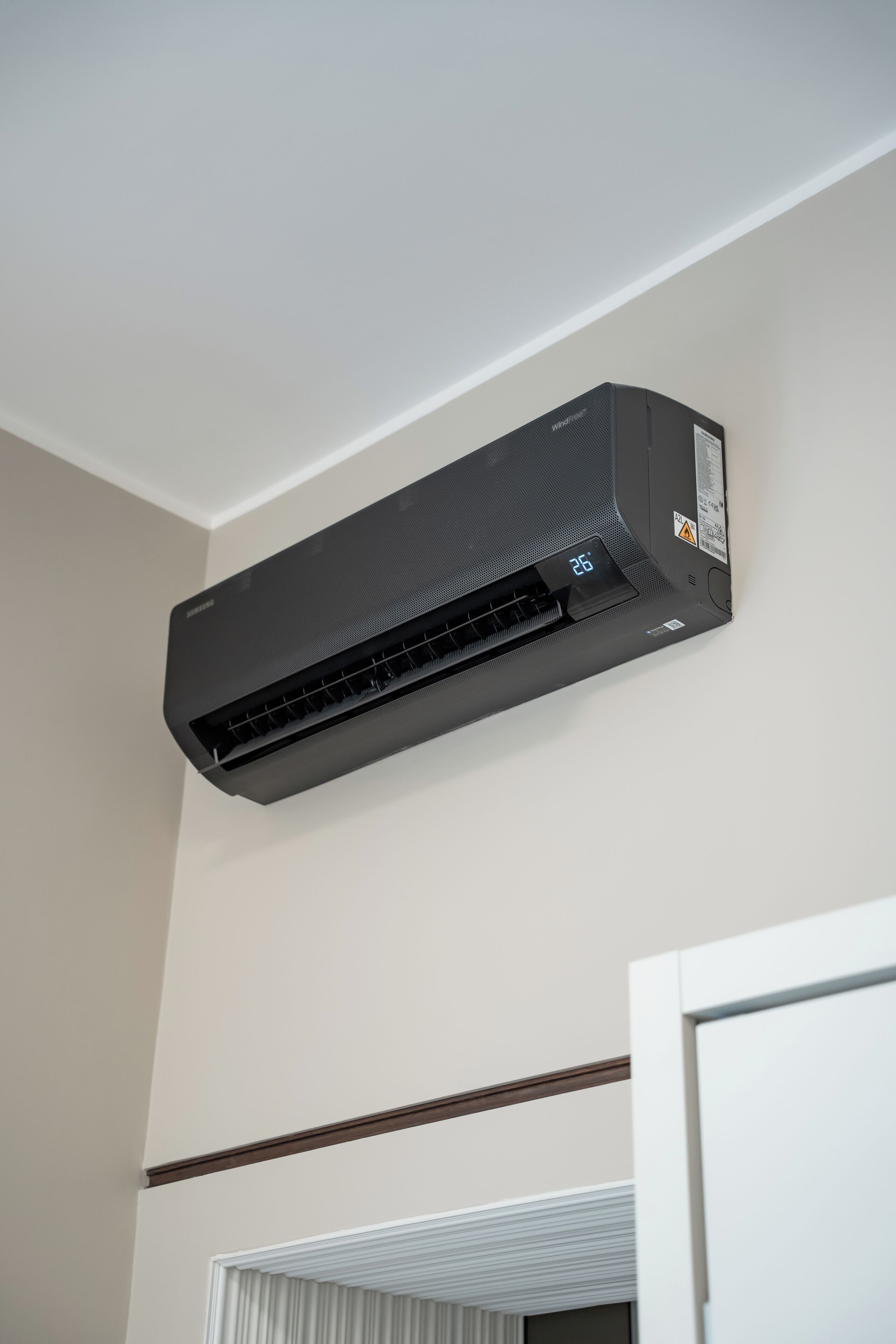 Un aire acondicionado de pared negro con pantalla digital.