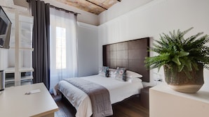 A modern bedroom with a large bed, a desk, a wardrobe, and a potted plant. - New Design St. Peter (Rome)