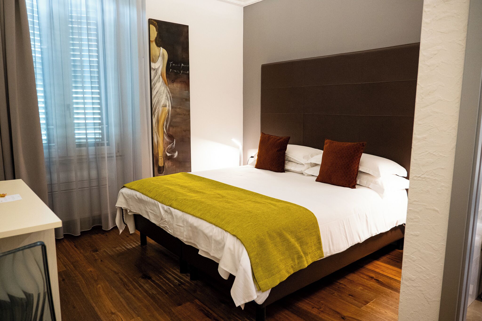 A hotel room with a large bed, a desk, and a window with curtains.