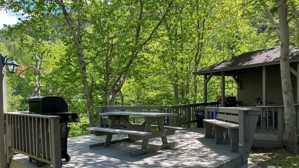 A wooden deck with picnic tables and a barbecue grill. - Georges Mountain Village (Steady Brook)