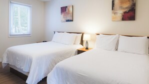 A hotel room with two beds, a window with blinds, a ceiling light, and two abstract paintings on the wall. - Georges Mountain Village (Steady Brook)